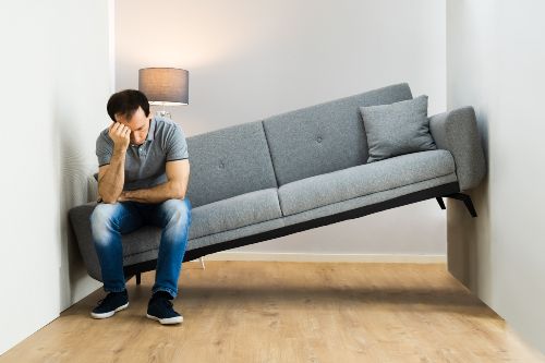 Man sitting on sofa stuck in hallway Man sitting on sofa stuck in hallway