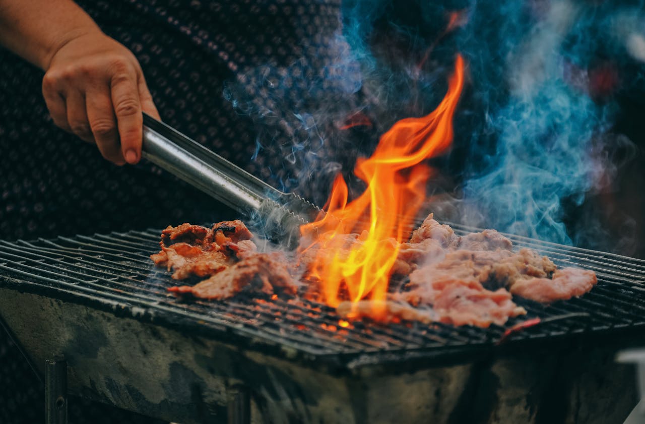 Person cooking food on a grill with fire Person cooking food on a grill with fire