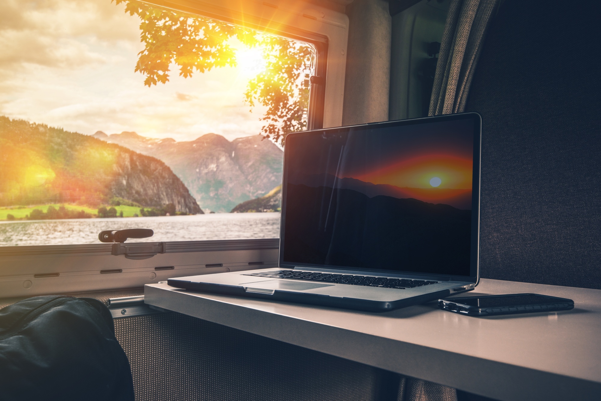 An open laptop on an RV table next to a window